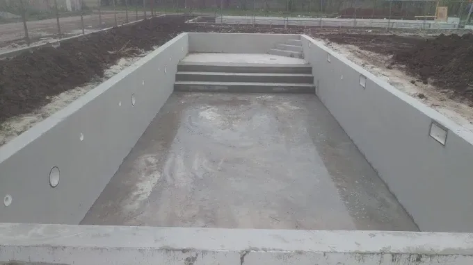 Bazin de piscină cu pereții și fundul netezite, cu piesele de trecere montate, înainte de liner